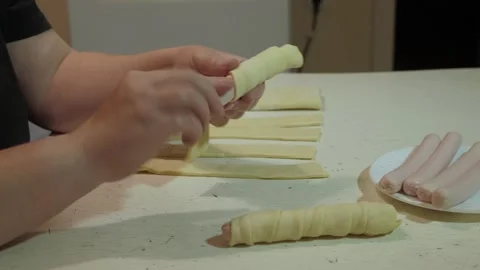 Hands wrapping dough strips around sausages Vidéo 342362610