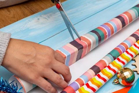 Hands wrapping gift on the background of wrapping paper and satin ribbons. Ho Stock Photos