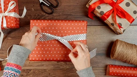 Hands wrapping present for holidays. Packaging wrapped gift box with bow. Stock Footage 117189988