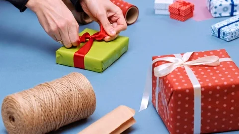 Hands wrapping present. Packaging wrapped gift box with ribbon and bow. Stock Footage 117190573