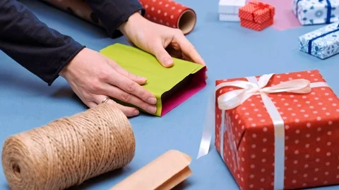 Hands wrapping present. Packaging wrapped gift box with ribbon and bow. Stock Footage 117190733