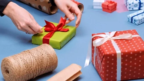 Hands wrapping present. Packaging wrapped gift box with ribbon and bow. Stock Footage 117190817