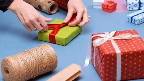 Hands wrapping present. Packaging wrapped gift box with ribbon and bow. Stock Footage 117191003