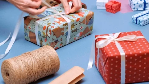 Hands wrapping present. Packaging wrapped gift box with ribbon and bow. Stock Footage 117191146