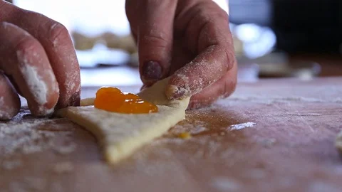 Hands wrapping raw dough stuffed with marmalade on a board close up time lapse Video stock 128680280