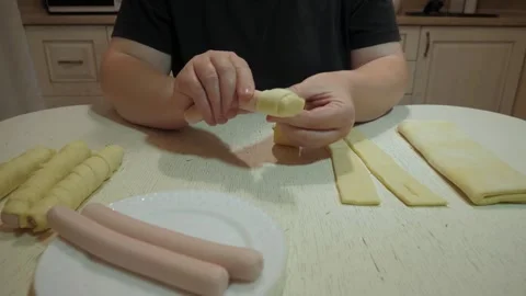 Hands wrapping sausages with thin dough strips Video stock 342362614