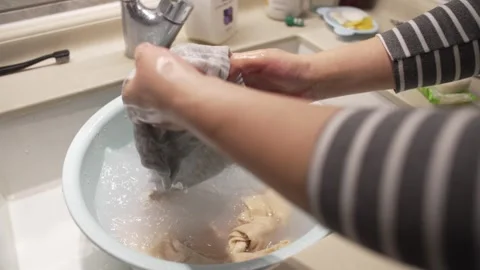 Hands Wringing Wet Grey Fabric Over Soapy Water Basin in Bathroom Stock Footage 337413835