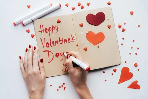 Hands write with a felt-tip pen in a sketchbook HAPPY VALENTINE'S DAY. Stock-Fotos