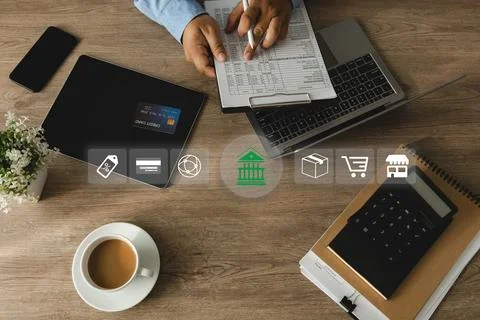 Hands write on financial document beside calculator, credit card, laptop, t.. Stock Photos