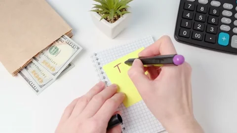 Hands write Tax Day note on yellow sticky paper. Stock Footage 168082364