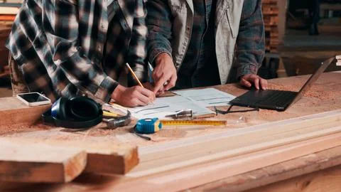 Hands, writing and documents in lumber workshop, carpenter and team with in.. Stock Photos