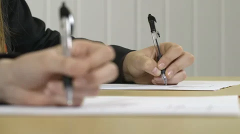 Hands writing in an exam or classroom with defocussed foreground Stock Footage 66547365