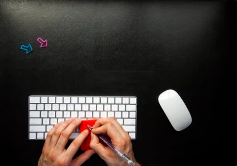 Hands writing a note on sticky note on desk 写真素材
