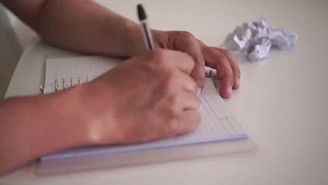 Hands writing in a notebook, making a mistake, crossing out text, and tearing Stock Footage 340323624