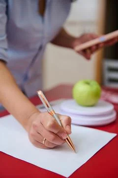 Hands writing notes with apple on table and digital tablet nearby Stock Photos
