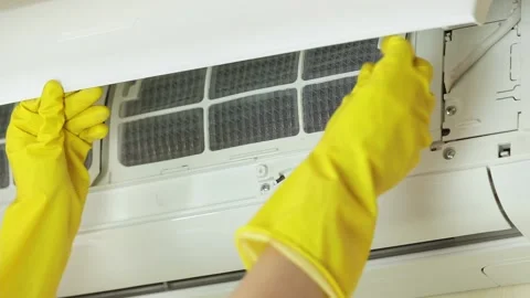 Hands in yellow gloves open front cover of air conditioner and remove filter for Stock Footage 158225261