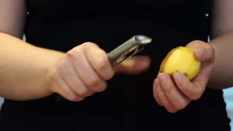 Hands with yellow potatoes and a paring knife close-up view. Peeling potatoes, c Stock-Footage 128628449