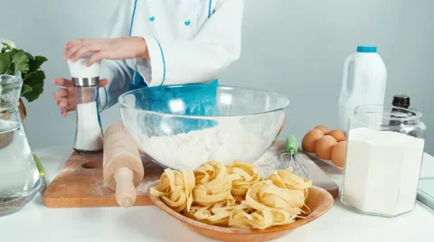 Hands of young baker using salt cellar and flour at the kitchen table Stock Footage 68093163