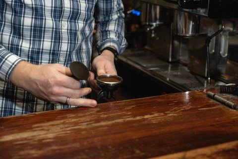 Hands of young bartender in uniform making espresso coffee on coffee machin.. Stock Photos