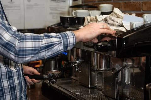 Hands of young bartender in uniform making espresso coffee on coffee machin.. Stock-Fotos