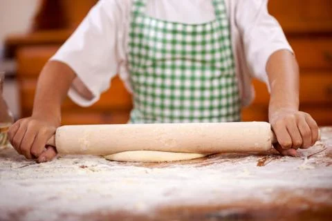 Hands of a young boy who pulls the dough in the kitchen Stock Photos