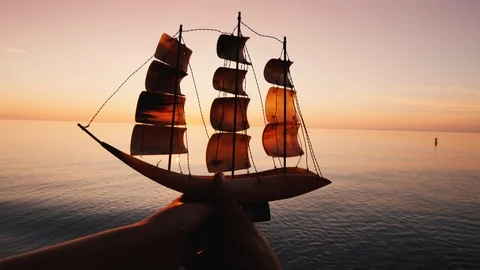 Hands of a young couple raise up a model of a sailing ship on the background of Stock Footage 116046187