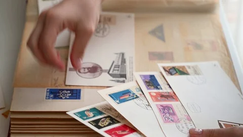The hands of a young girl are sorting through old envelopes with beautiful co Stock Footage 110419644