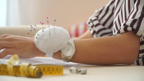 Hands of a young girl with clock, smooth white cloth. Seamstress making notes on Stock Footage 102615312