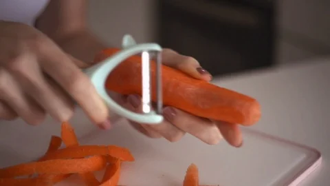 Hands of a young girl rub an orange carrot using a grater. Preparing carrot. Stock Footage