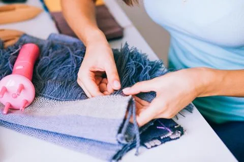 Hands young girls make brushes on a gray scarf, handmade scarf Stock Photos