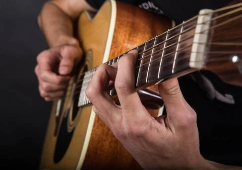 Hands of a young guy who plays guitar. Stock Photos