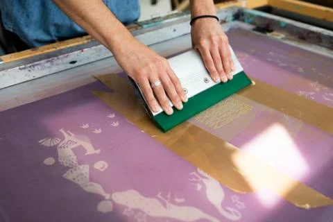 Hands of young male printer using squeegee in printing press studio Foto stock