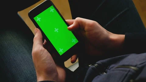 Hands of a young man are holding a smartphone with a green screen Stock Footage 103689447