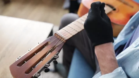 Hands of a young man changing the string on an acoustic guitar. Stockbeeldmateriaal 303778474