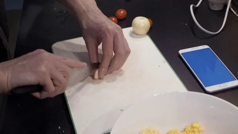 Hands of young man cutting garlic at home kitchen. Chroma key smartphone Stock Footage 74160137