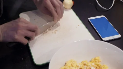 Hands of young man cutting garlic at home kitchen. smartphone Stock Footage 74160515