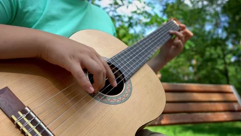The hands of a young man fingering the strings of a classical guitar outdoor in Stock Footage 205033818