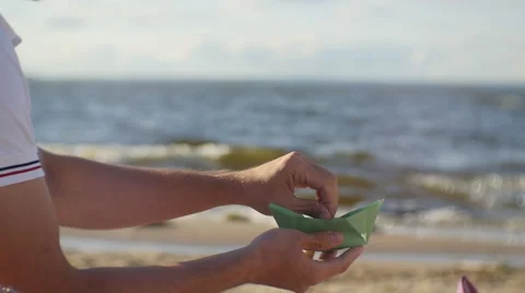  Hands the young man passed the green paper boat. On the beach Stock Footage 60843974