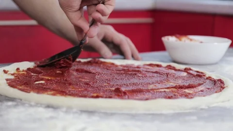 Hands of a young man put and smear tomato paste on pizza dough close up 動画素材 127689734