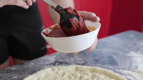 Hands of a young man put and smear tomato paste on pizza dough 動画素材 127695429