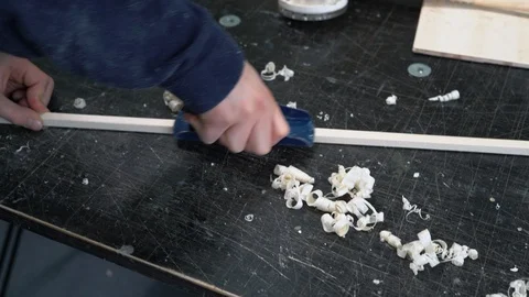 Hands of a Young Man Remove a Layer of Wood from a Wooden Bar with the Help of a Stock Footage 86658548
