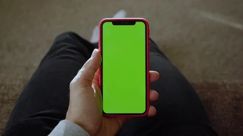 Hands young man sitting on sofa use hold vertical green screen phone at home Stock Footage 118472672
