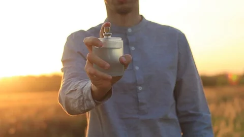 Hands of a young man using perfume at sunset Stock Footage 94170226