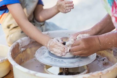 Hands of young potter, creating an earthen jar on the circle, close-up Stock Photos