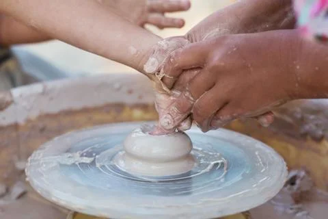 Hands of young potter, creating an earthen jar on the circle, close-up Stock Photos