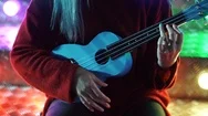 Hands Of Young Pretty Girl Playing On Blue Ukulele While Sitting On Glowing Neon Stock Footage