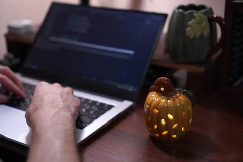 Hands of young programmer holding mug with coffee pumpkin drink working on .. Fotos de archivo