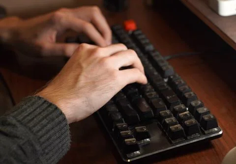 Hands of a young programmer working on a keyboard on a wooden table Stock-Fotos