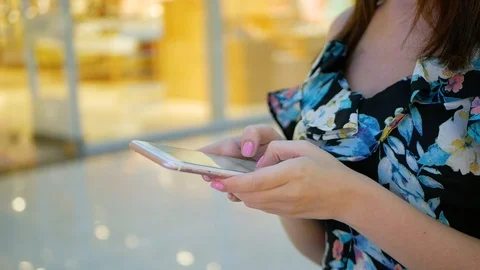 Hands of a young woman using mobile phone in modern shopping mall. Video stock 99351158