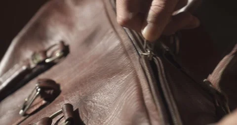 Hands Zipping Open Old Leather Travel Bag in Cinematic Light Stock Footage 344348105